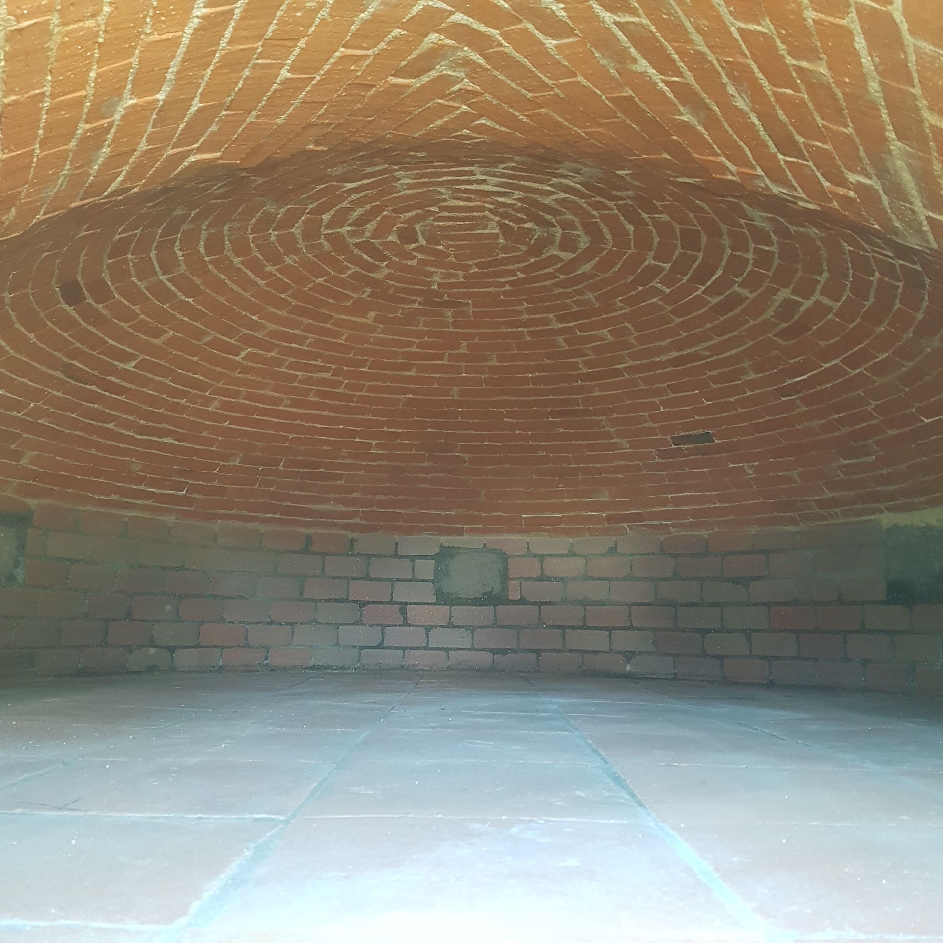 Vue intérieure en briques avec un plafond en dôme, une façade ouverte et un sol carrelé.