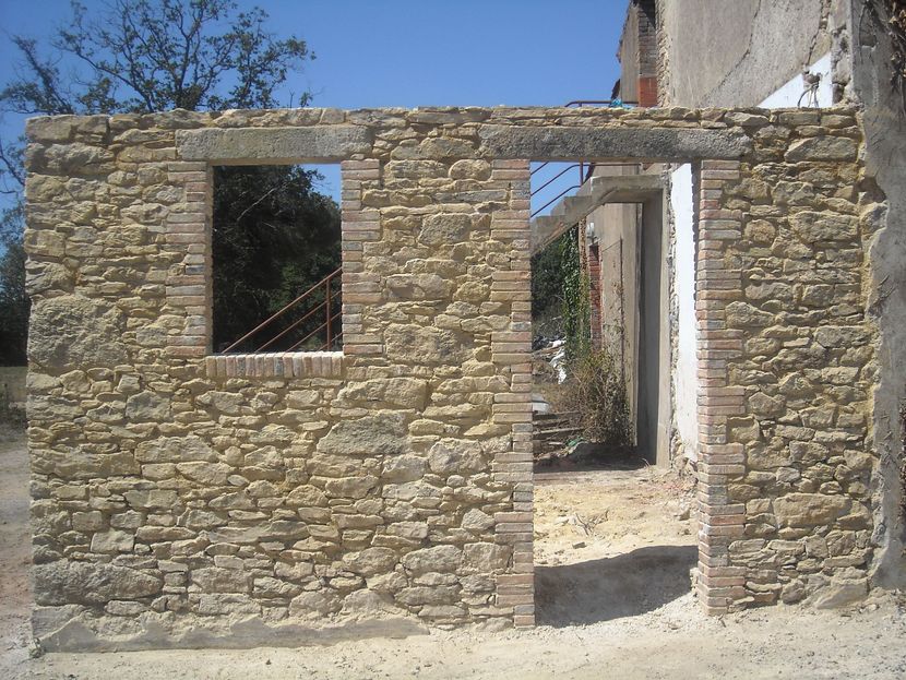 Mur en pierre et en brique avec une ouverture de porte et fenêtre, à l'extérieur.
