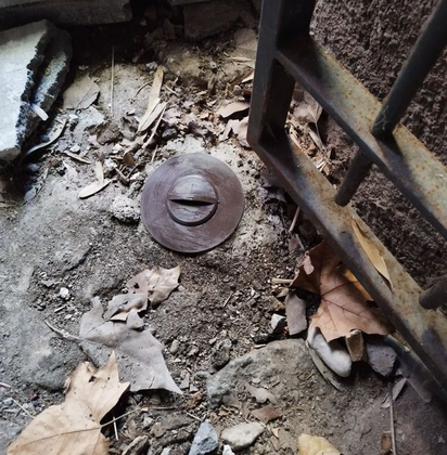 Un piège à termites enterré à côté d'une grille.