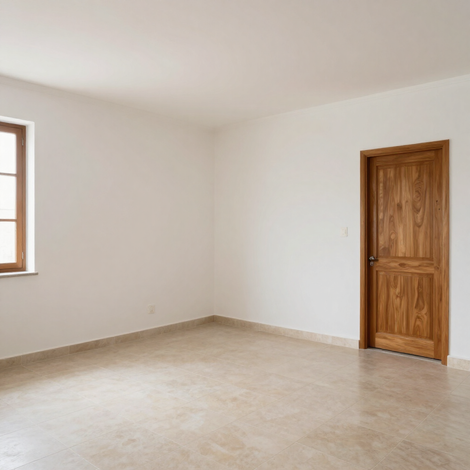 Habitación vacía de color beige, con paredes blancas, una ventana pequeña y una puerta de madera