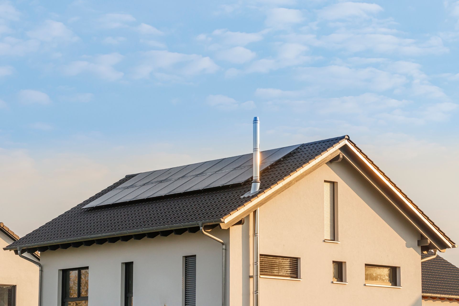 Haus mit Solarzellen auf dem Dach vor blauem Himmel.