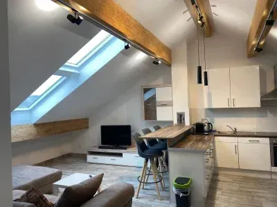 Innenansicht einer Wohnung mit Küche, Wohnbereich unter Dachschräge mit Oberlicht.