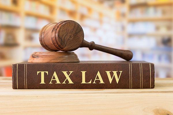 A wooden gavel is sitting on top of a book titled tax law.