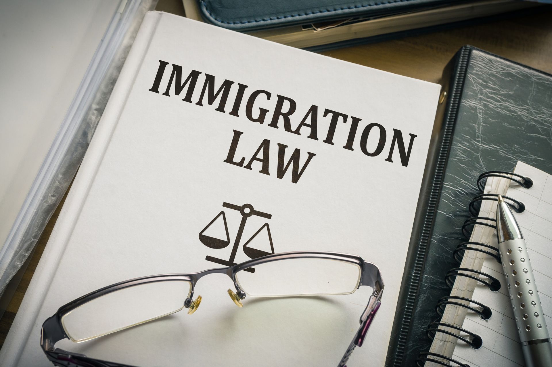 A book titled immigration law is sitting on top of a notebook.