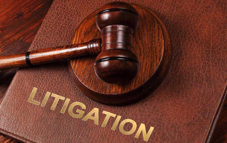 A wooden judge 's gavel is sitting on top of a book titled litigation.