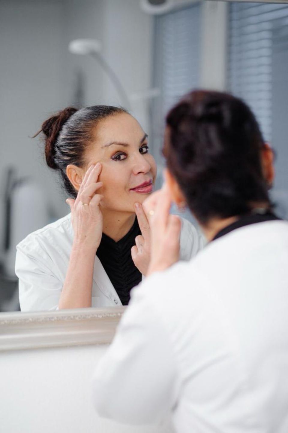 Eine Frau betrachtet ihr Gesicht im Spiegel.