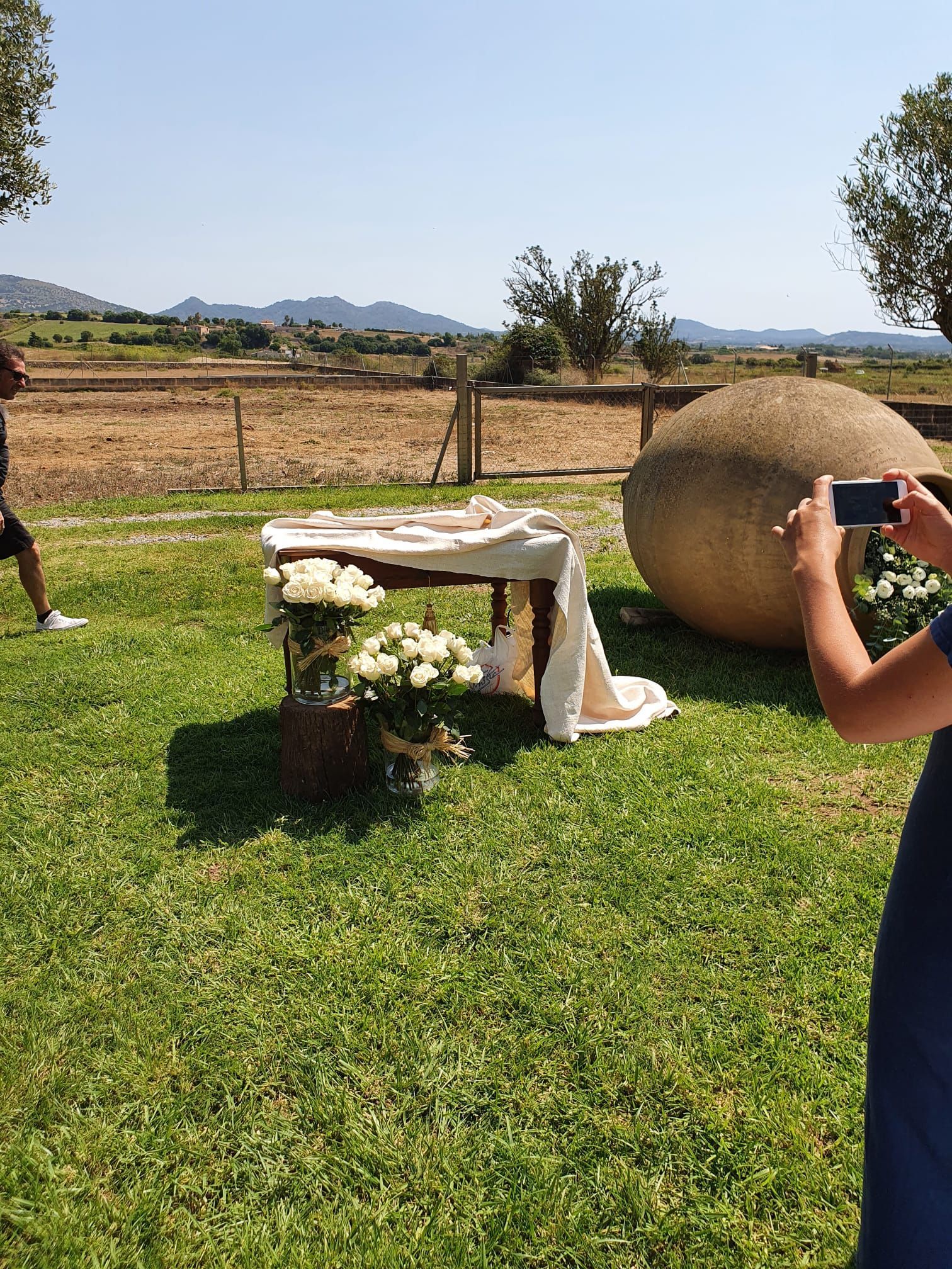 Una mujer está tomando una fotografía de una mesa con flores en un campo.