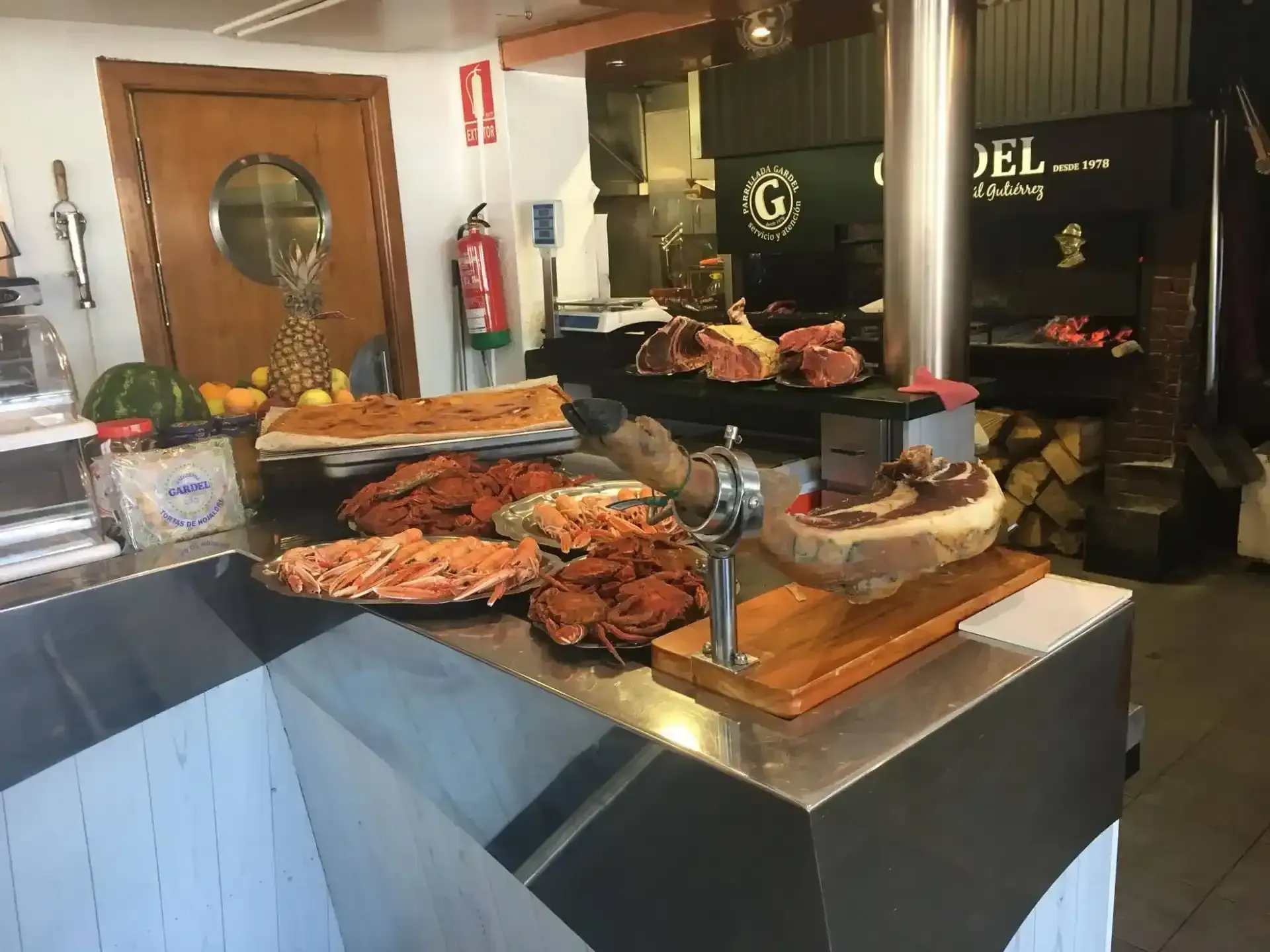 Mostrador con diversos alimentos cocinados y una pierna de jamón, en un restaurante.