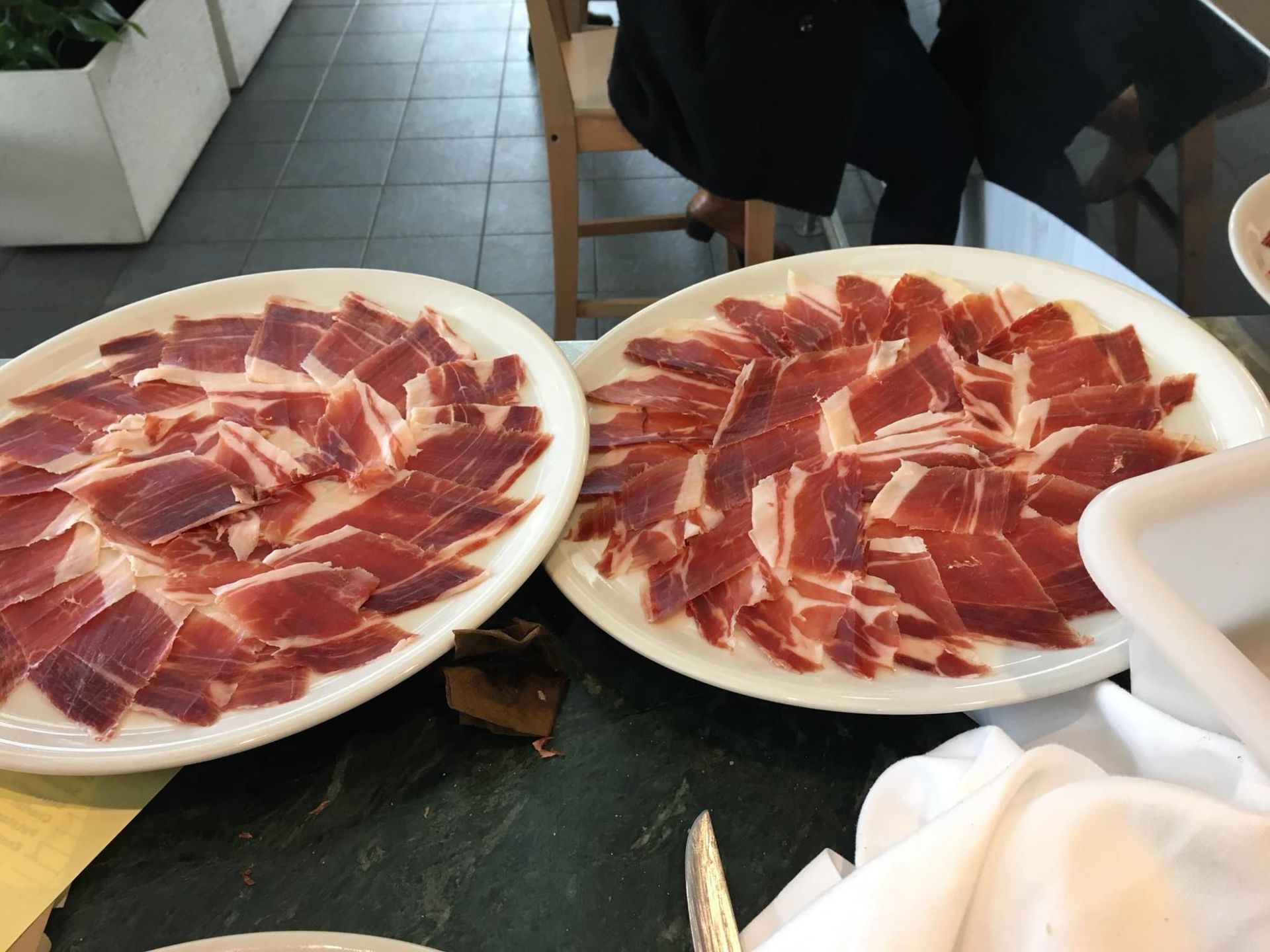 Dos platos blancos con carne curada cortada fina.