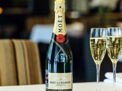 Botella de champán Moët & Chandon con dos copas llenas sobre una mesa.