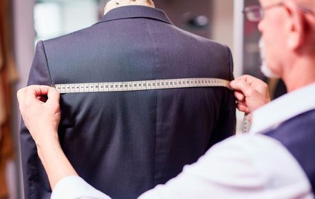 Un sastre está midiendo la espalda de un traje en un maniquí.