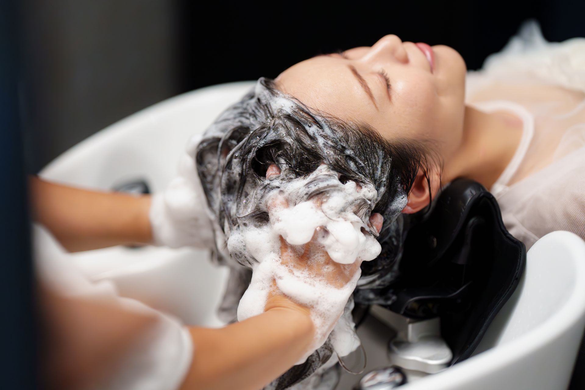 Einer Frau werden in einem Waschbecken in einem Salon die Haare gewaschen.