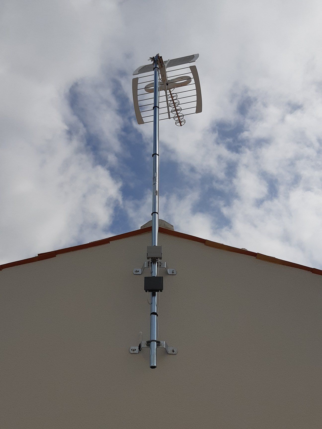 Une antenne de télévision extérieure montée sur le toit d'une maison contre un ciel nuageux.