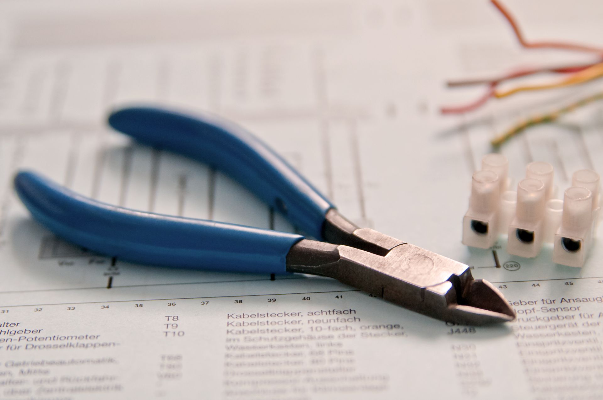 Coupe-fils à manche bleu sur un schéma, avec connecteurs de fils et fils colorés.