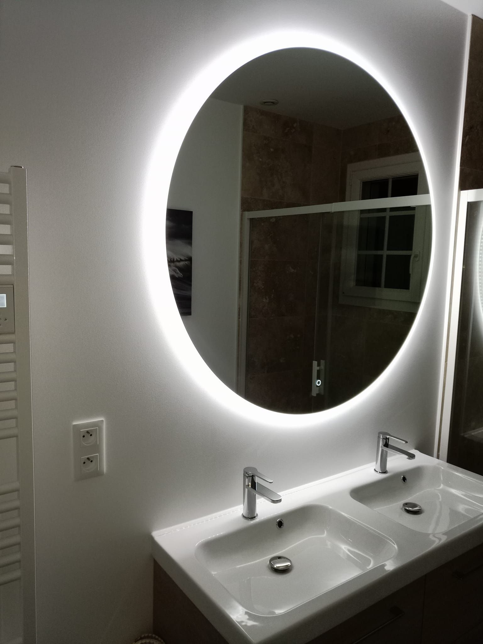 Miroir de salle de bains circulaire avec éclairage LED intégré au-dessus d'un meuble-lavabo double.