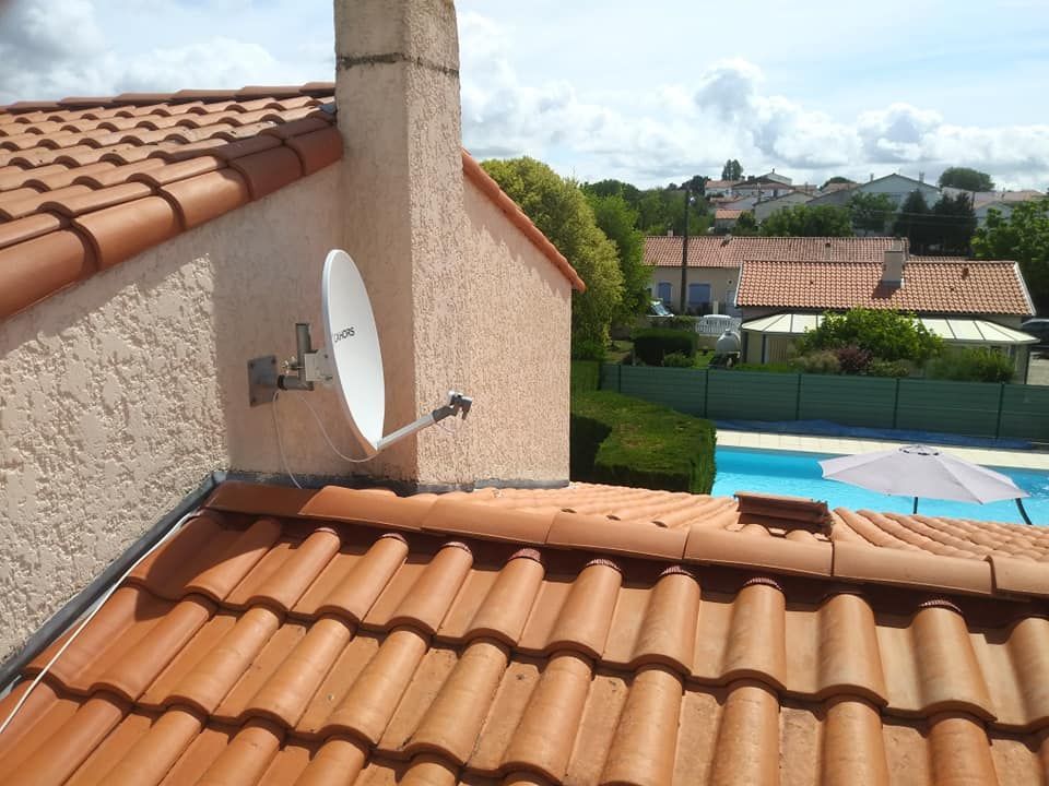 Antenne parabolique montée sur un toit près d'une cheminée, surplombant une piscine et un quartier de banlieue.