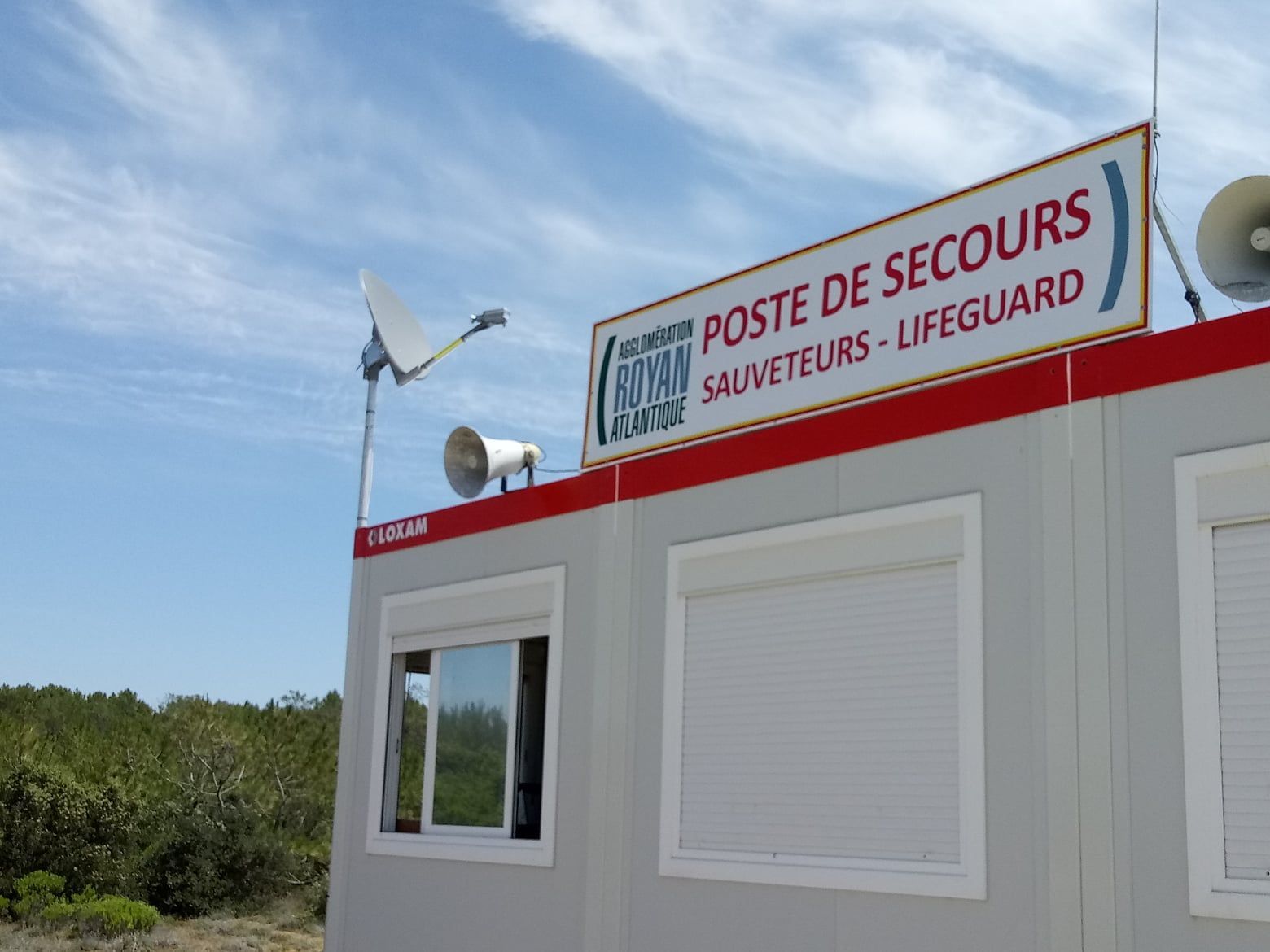 Poste de secours avec panneau POSTE DE SECOURS - LIFEGUARD sous ciel bleu.