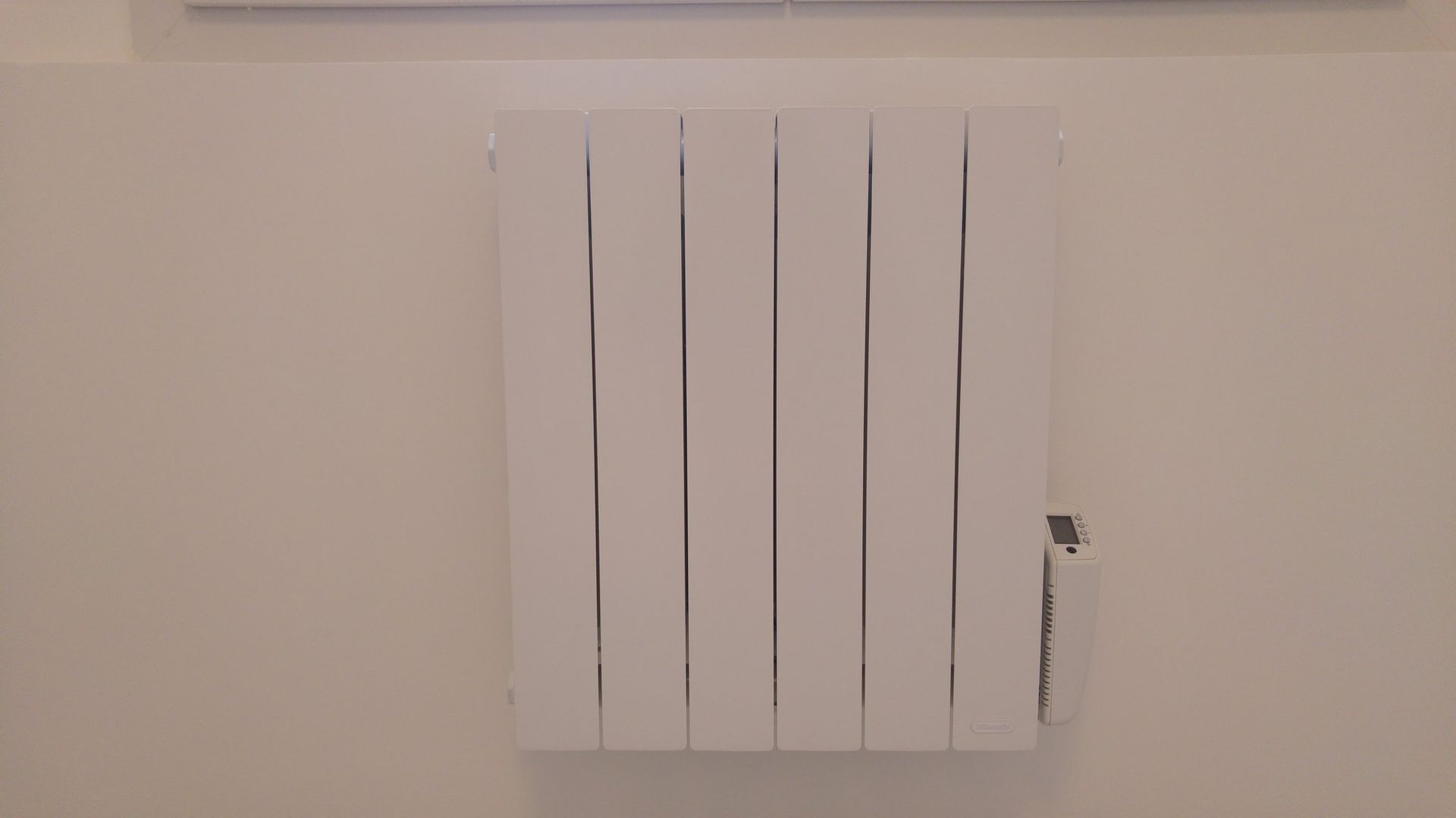 Radiateur mural blanc sur un mur de couleur claire.