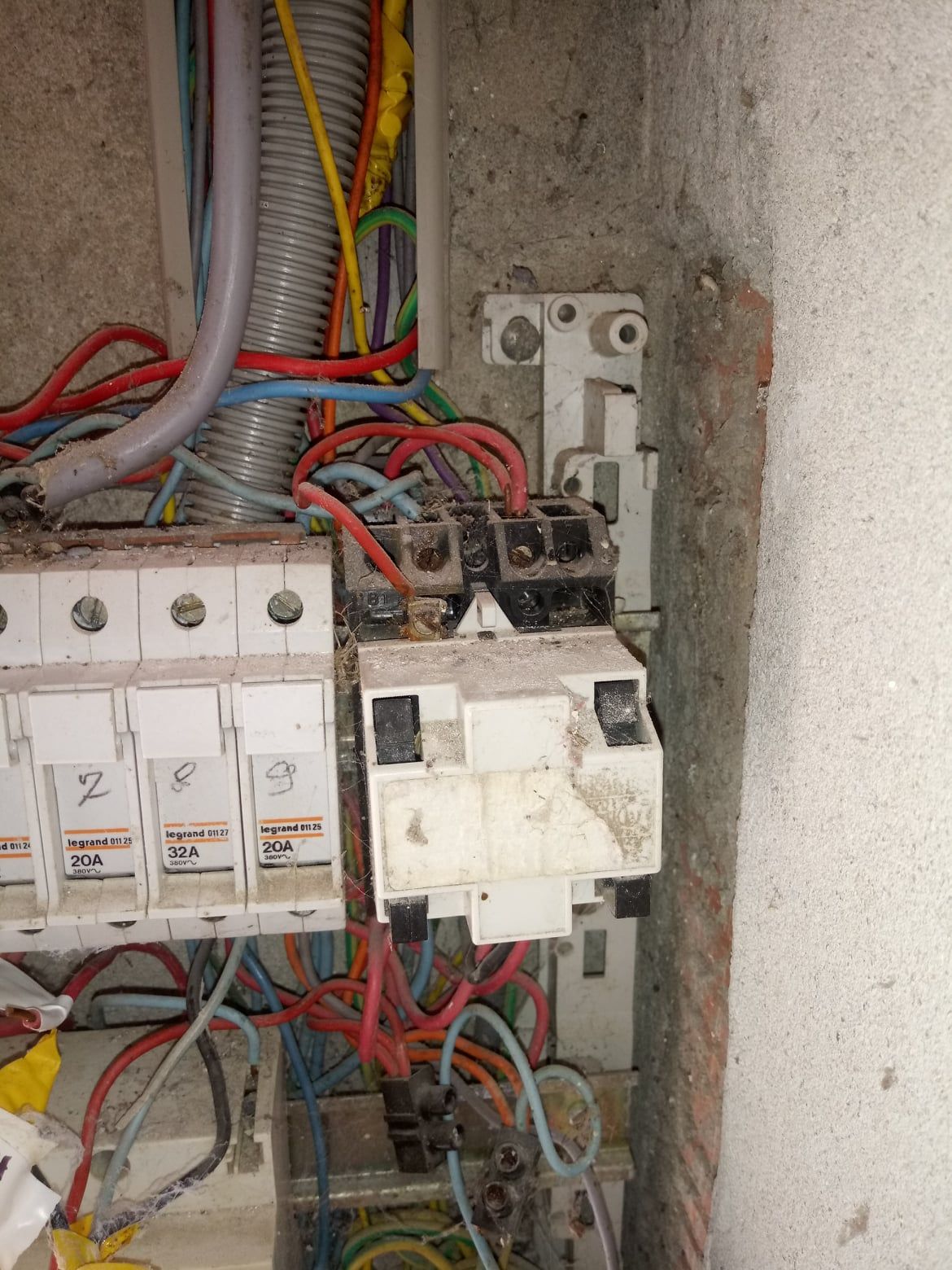 Tableau électrique avec câblage et composants brûlés. Fils rouges, bleus et jaunes.