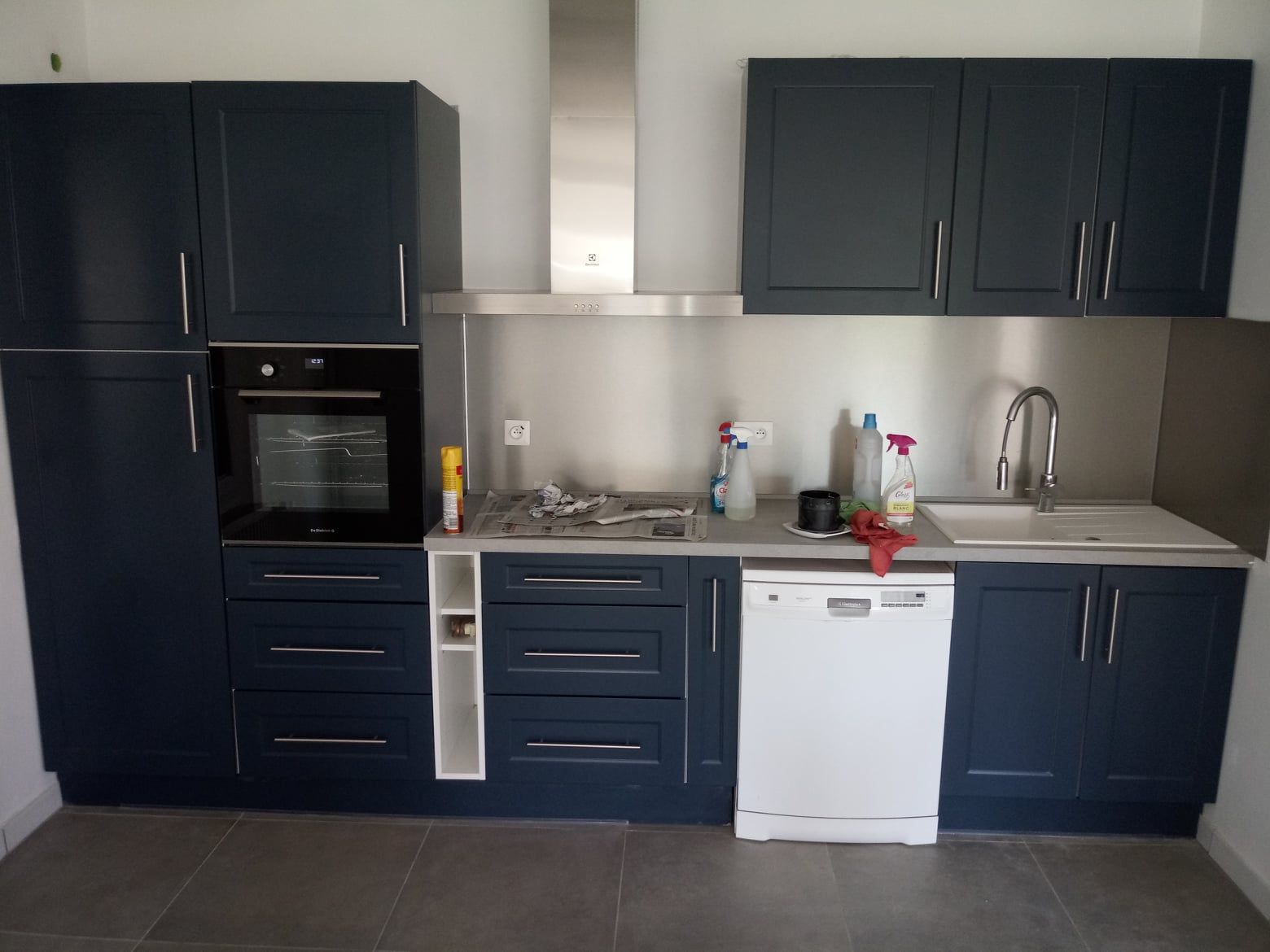 Armoires de cuisine bleu foncé et électroménager, prises et éclairages