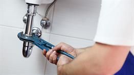 Ein Klempner repariert ein Waschbecken mit einem Schraubenschlüssel.