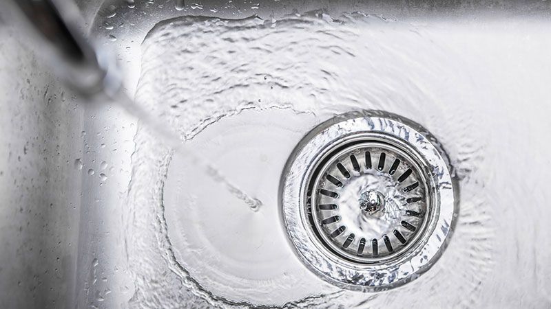 Eine Nahaufnahme eines Spülbeckens, aus dessen Abfluss Wasser läuft.
