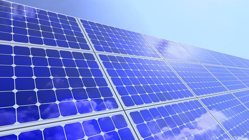 Eine Reihe blauer Solarmodule vor blauem Himmel