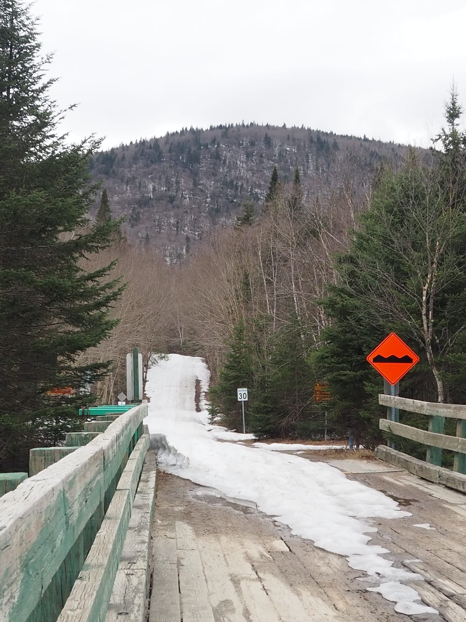 Pont en bois recouvert de neige et montagne en arrière plan
