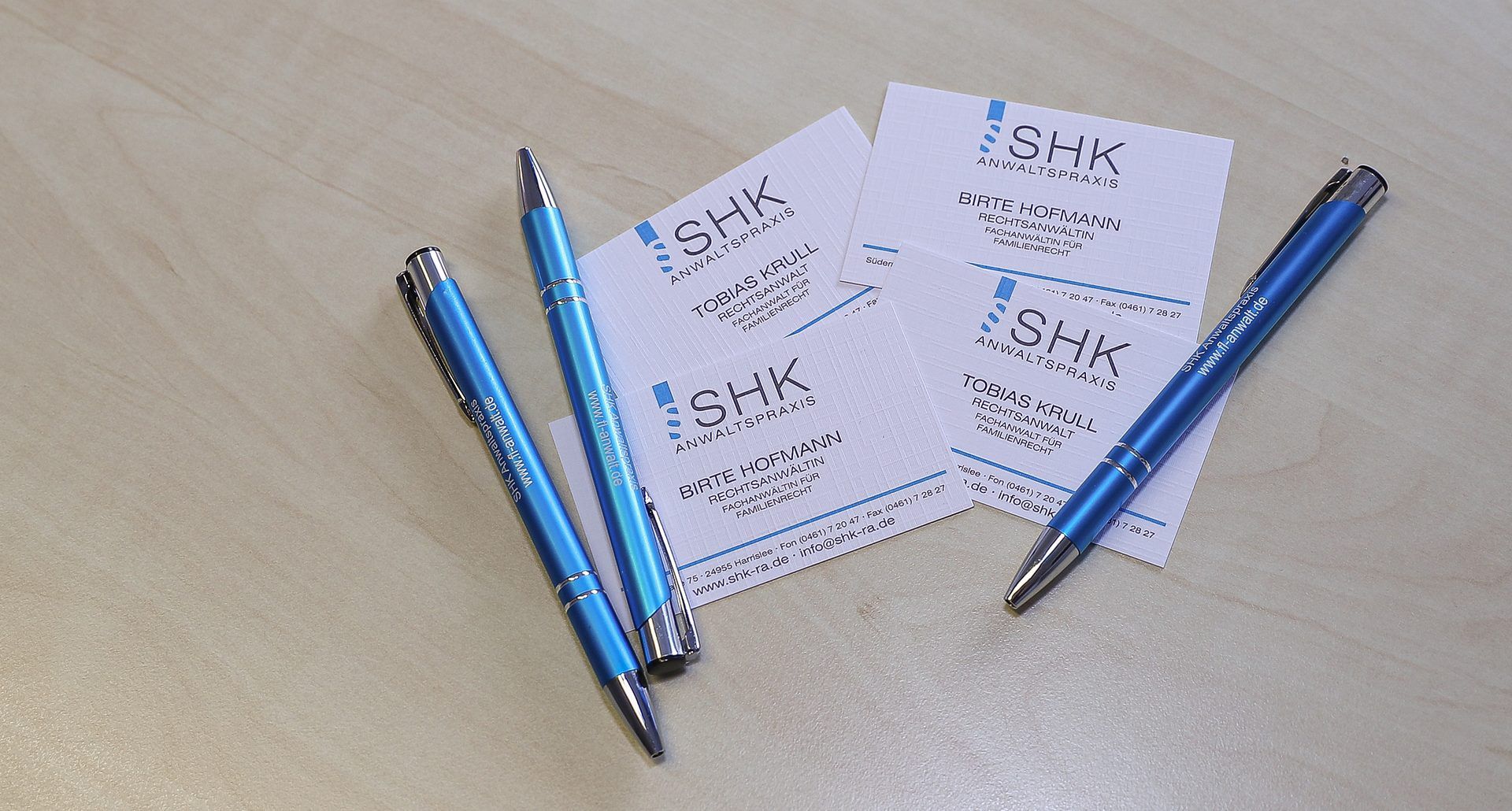 Drei blaue Stifte liegen auf einem Stapel Karten.