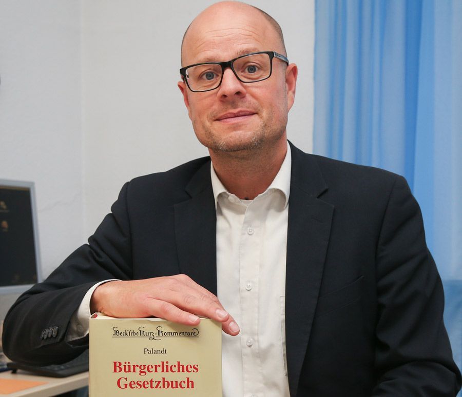 Ein Mann in Anzug und Brille schreibt auf ein Stück Papier