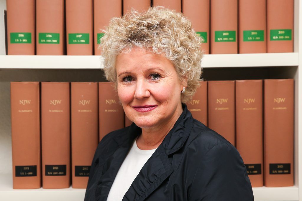 Eine Frau steht vor einem Regal voller Bücher.