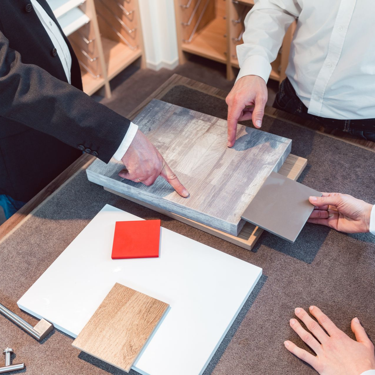 Des personnes dans un studio de design présentent différents échantillons de matériaux pour un projet de rénovation.