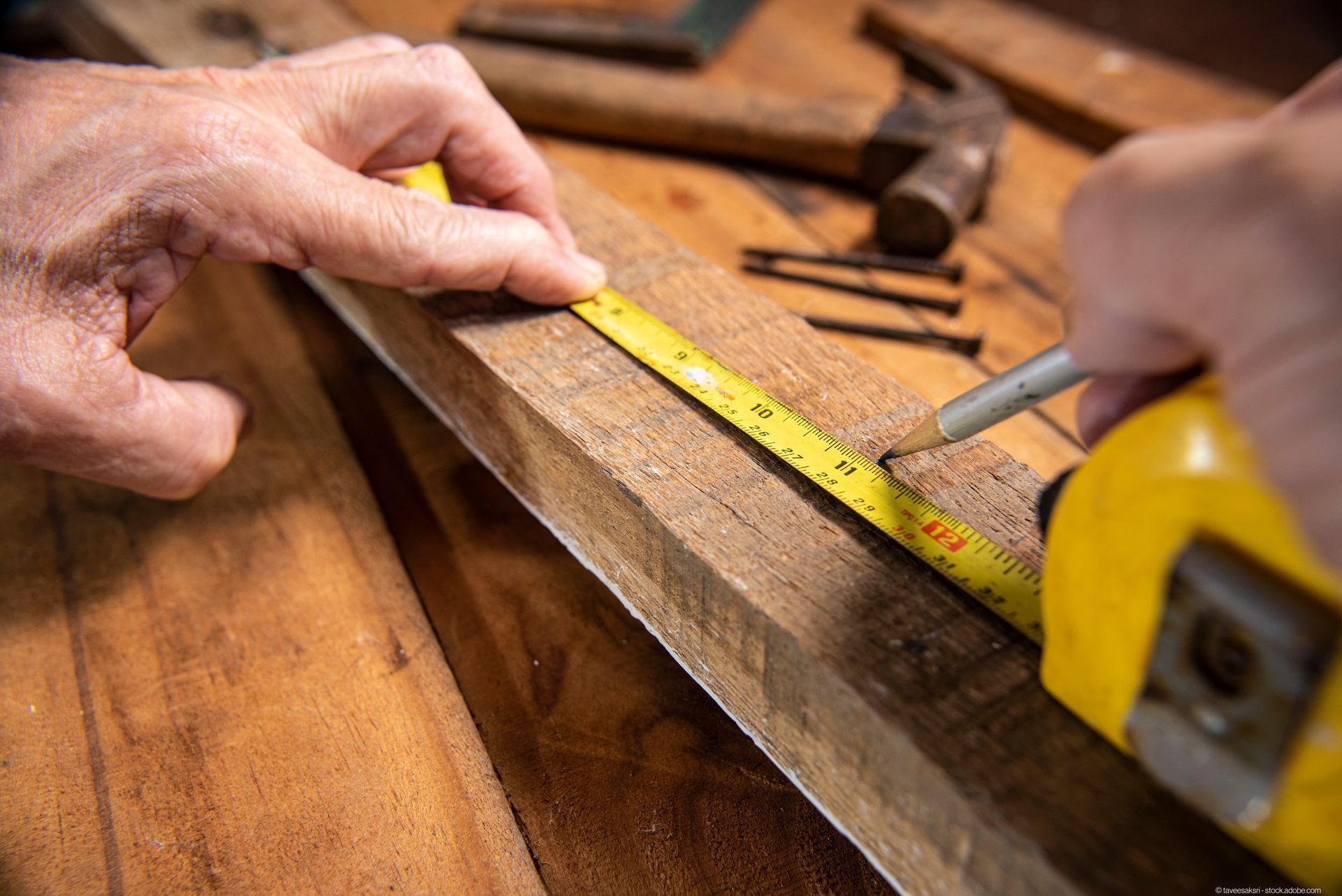 Ein Mann misst ein Stück Holz mit einem Lineal
