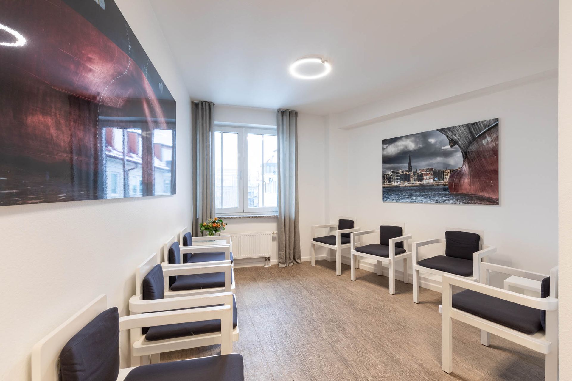 ein Wartezimmer mit vielen Stühlen und einem Gemälde an der Wand.