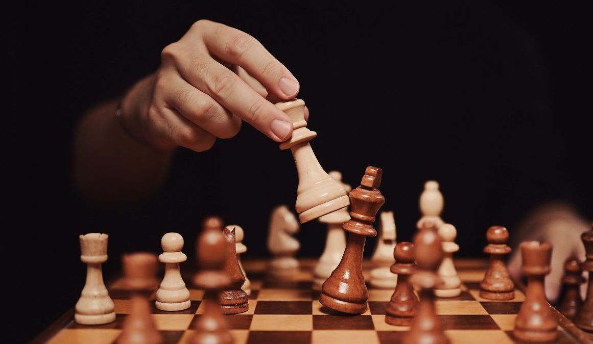 Una persona está jugando una partida de ajedrez en un tablero de ajedrez.