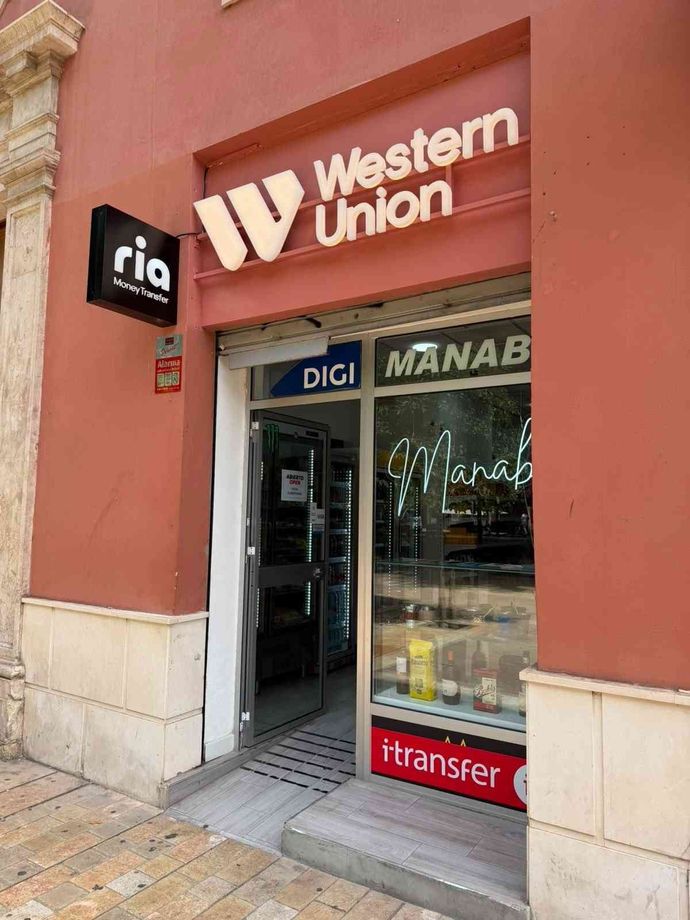 Smartphone con aplicación de billetera digital junto a tarjetas de crédito y monedas, lo que sugiere pagos móviles.