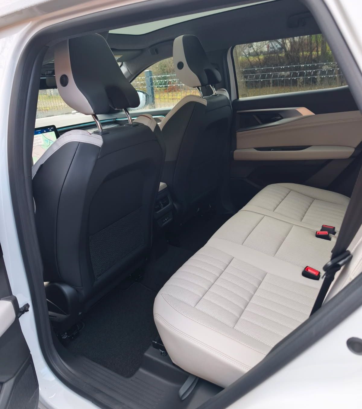 Cinq voitures stationnées : des berlines bleues et rouges, une camionnette bordeaux. Parking en gravier, arbres en arrière-plan.