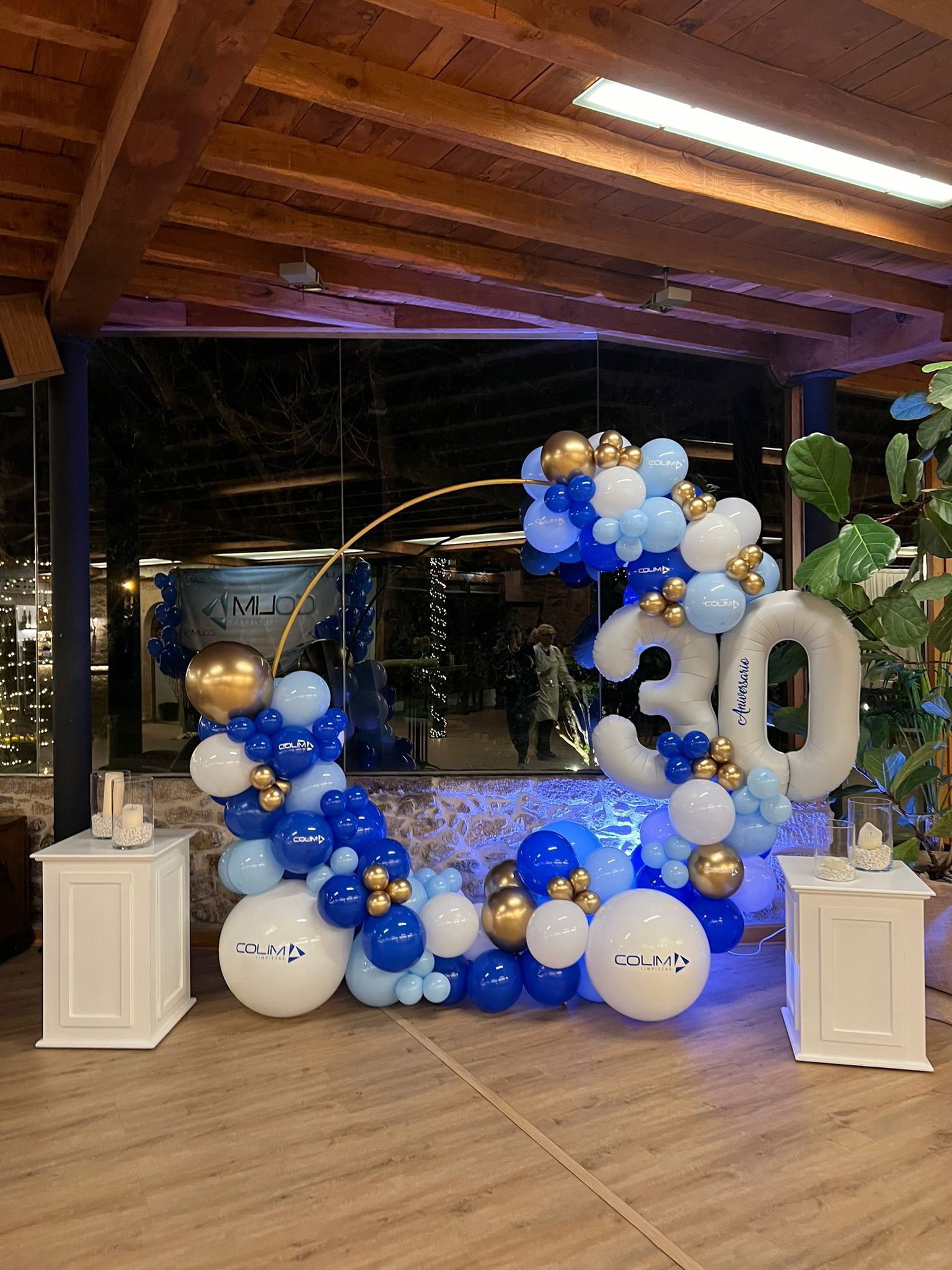 Un automóvil está estacionado en una sala de exposición decorada con globos rojos, blancos y plateados.