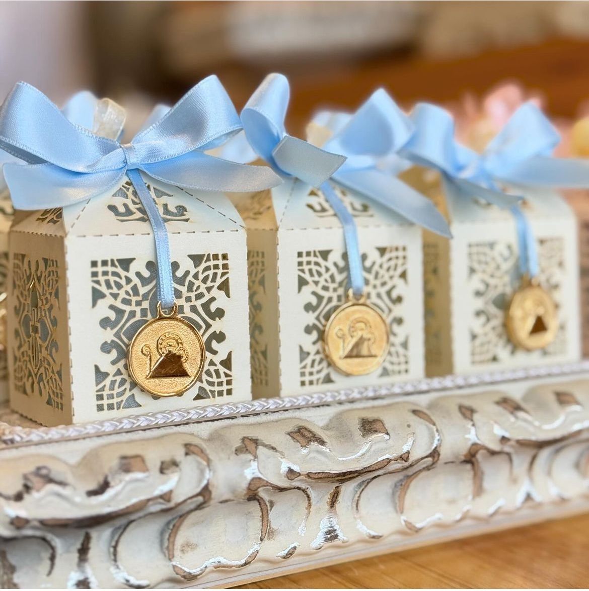 Una fila de cajas blancas con lazos azules y medallones dorados