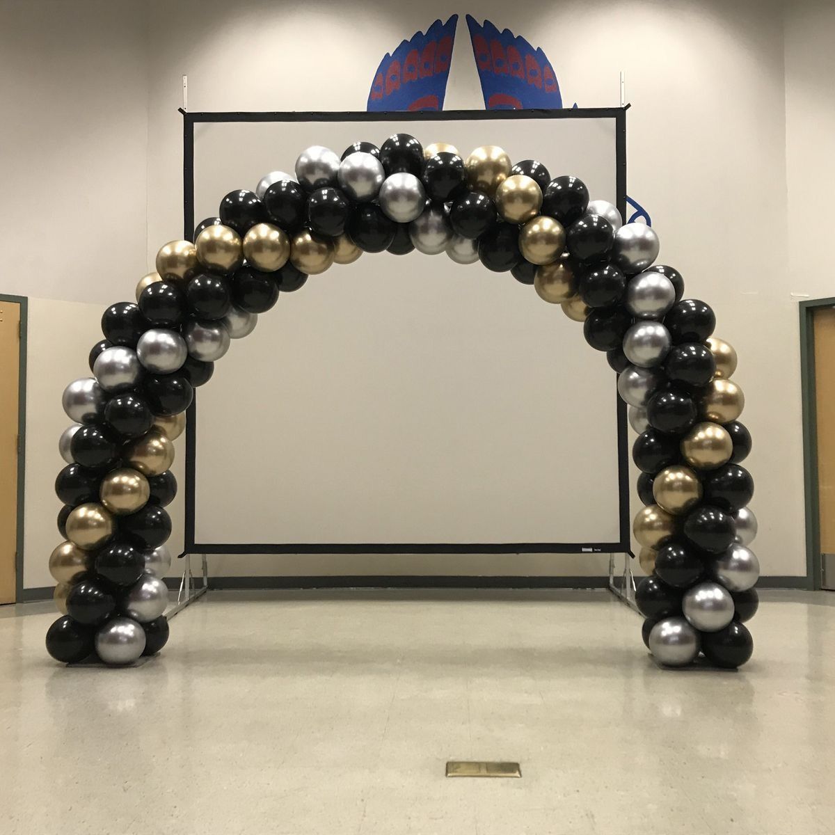 Un gran arco hecho de globos de oro negro y plata.