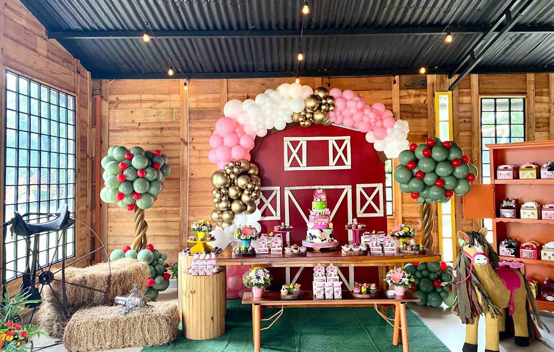 Un granero decorado con globos y fardos de heno para una fiesta de cumpleaños.