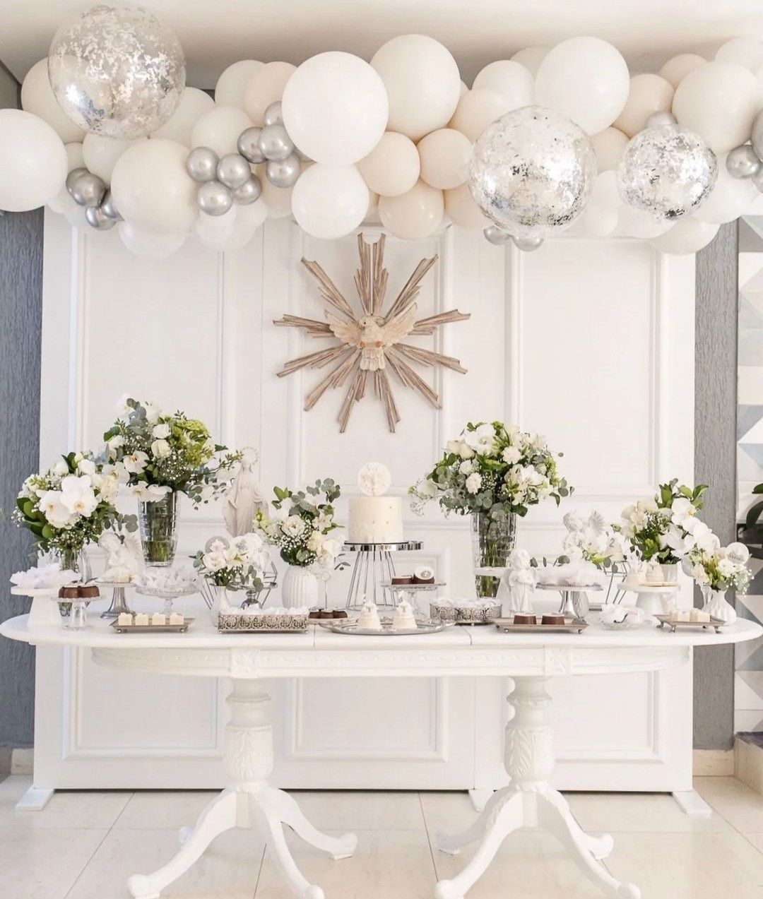 Una mesa blanca con flores y globos encima.