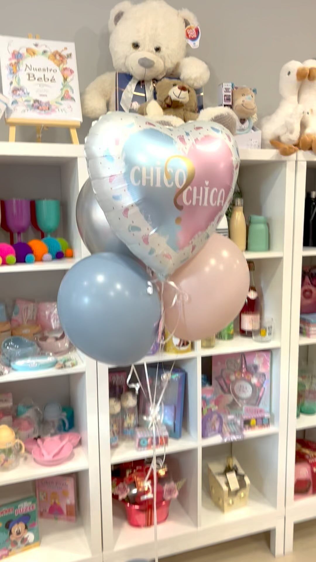 Un montón de globos están colocados en la parte superior de un estante en una tienda.