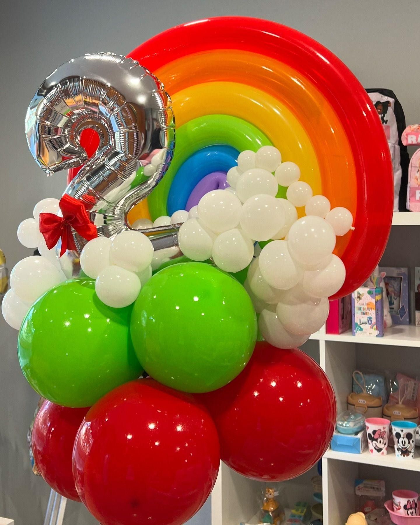 Un montón de globos con un arcoíris y el número 2 en él.