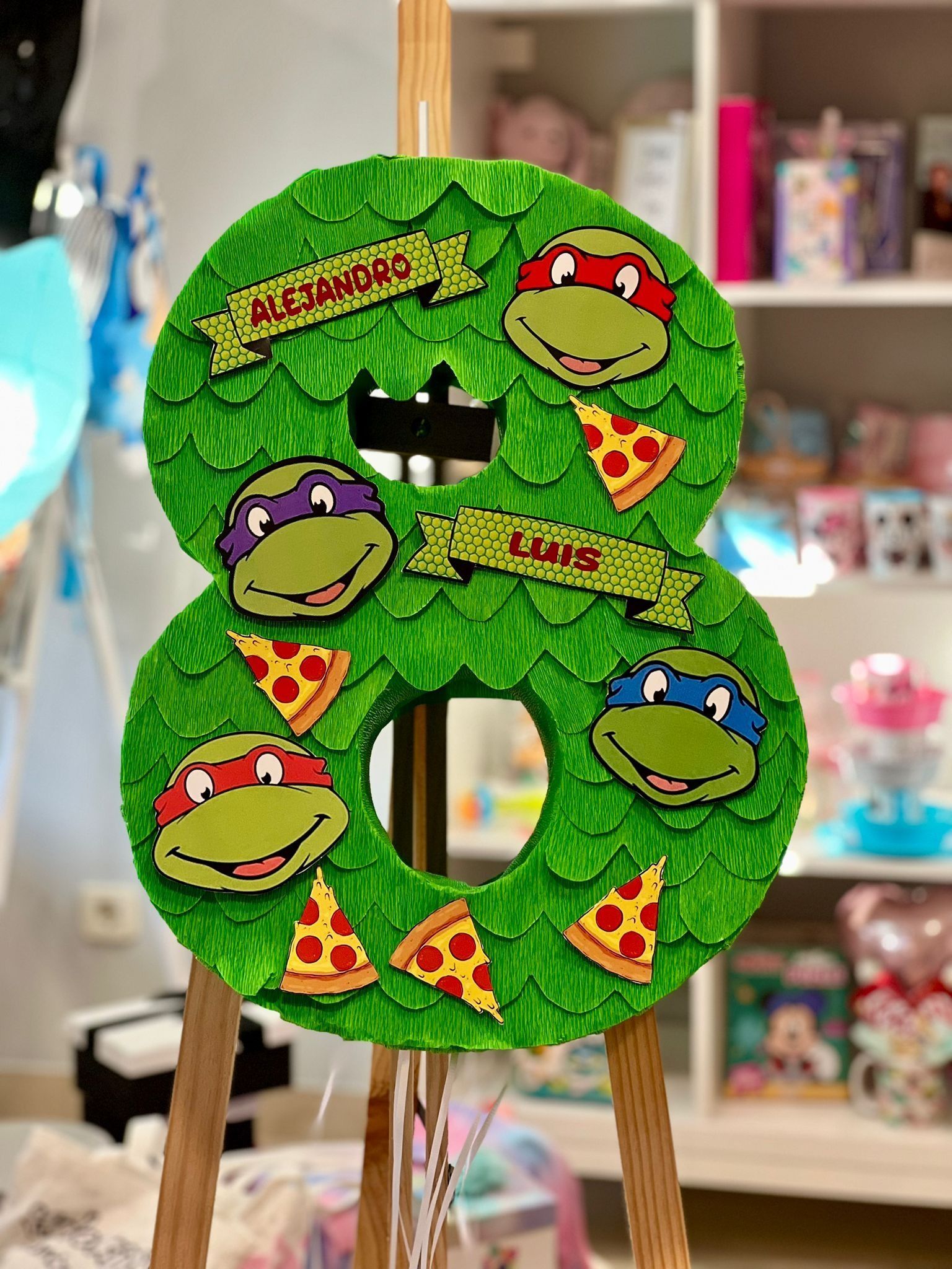 Un número ocho con las Tortugas Ninja Adolescentes Mutantes sobre él está sentado sobre un caballete de madera.