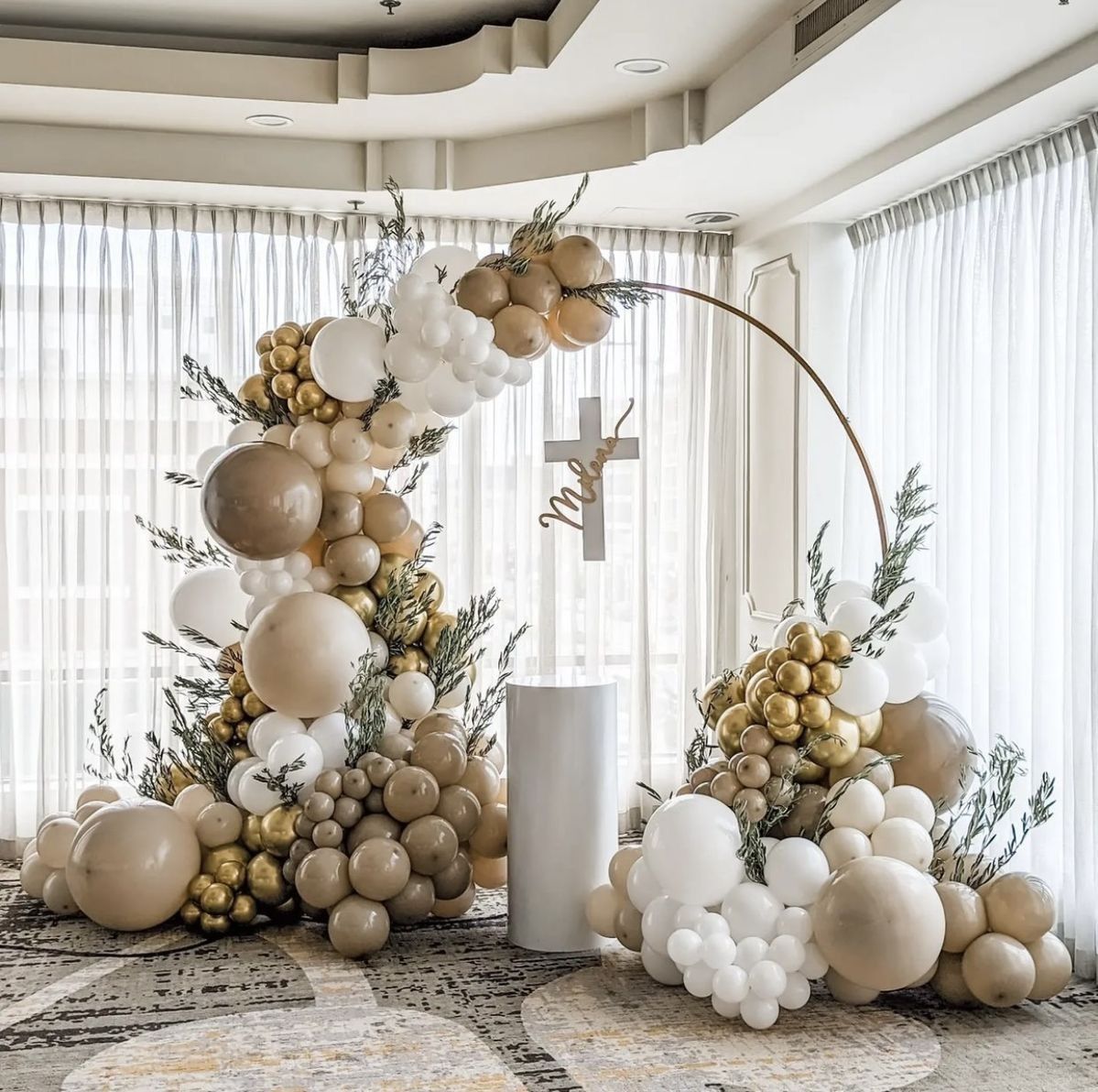 Una habitación llena de globos y flores con una cruz en el medio.