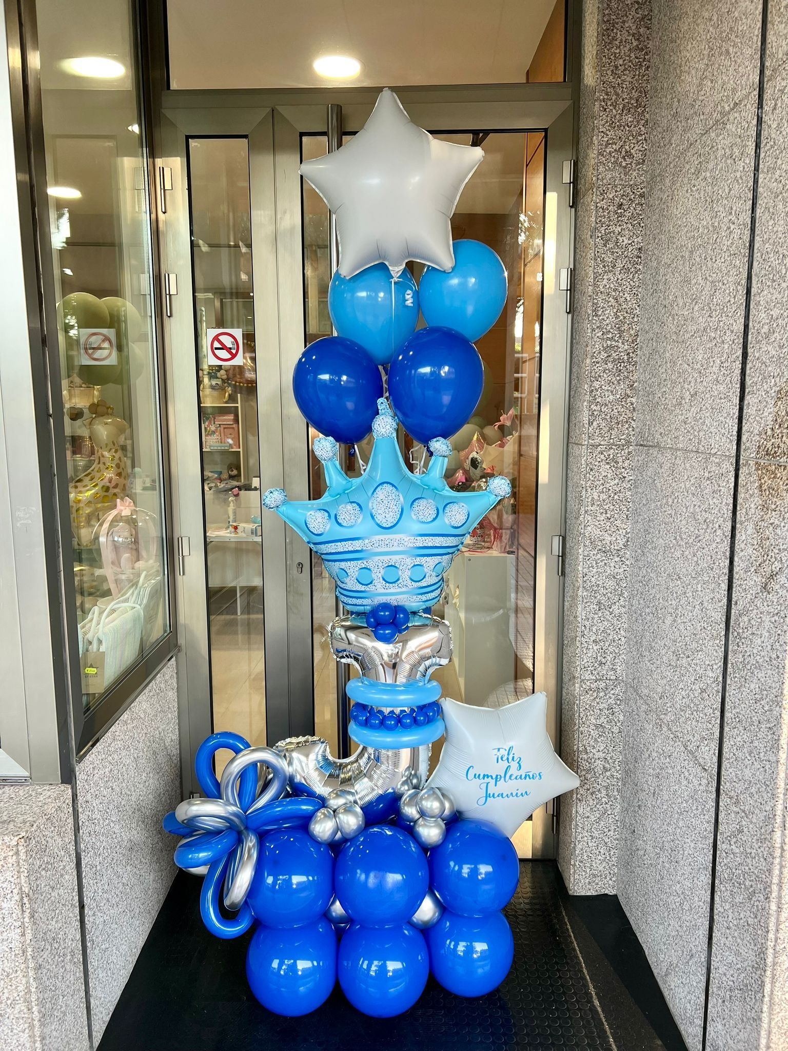 Un montón de globos azules y plateados con una corona encima de ellos.