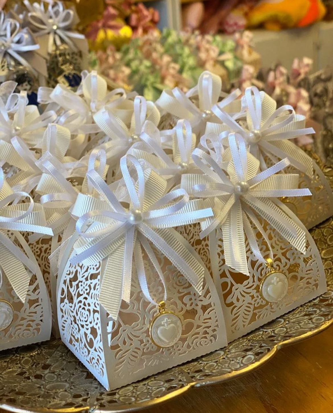 Un montón de cajas blancas con lazos están sobre una mesa.