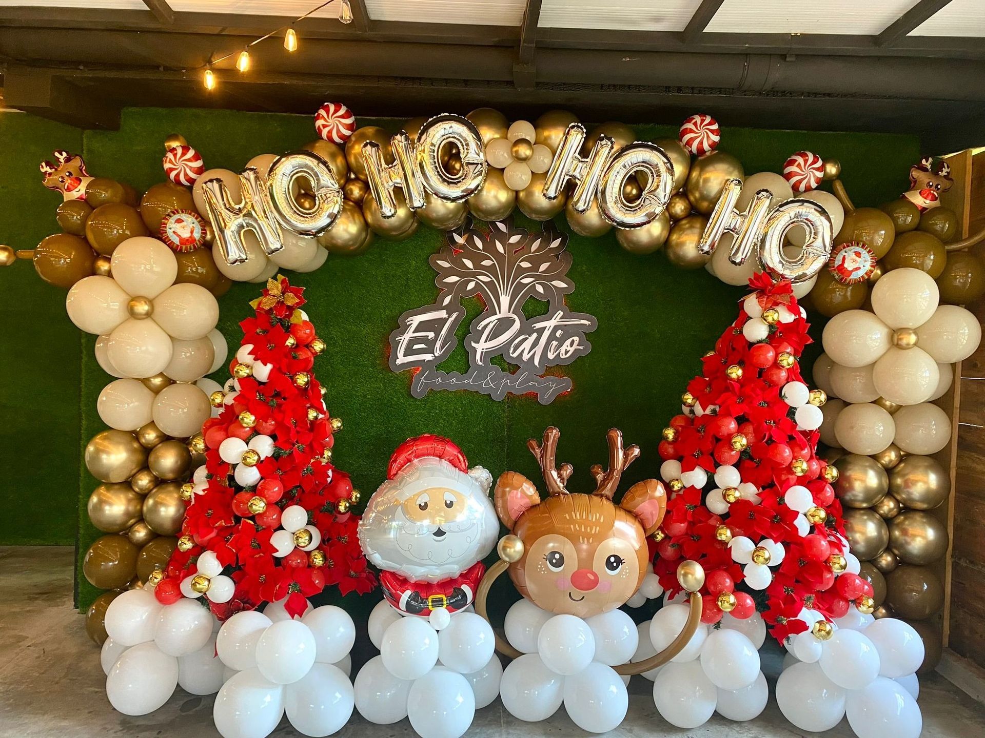 Una pared decorada con globos y árboles de navidad para una fiesta navideña.