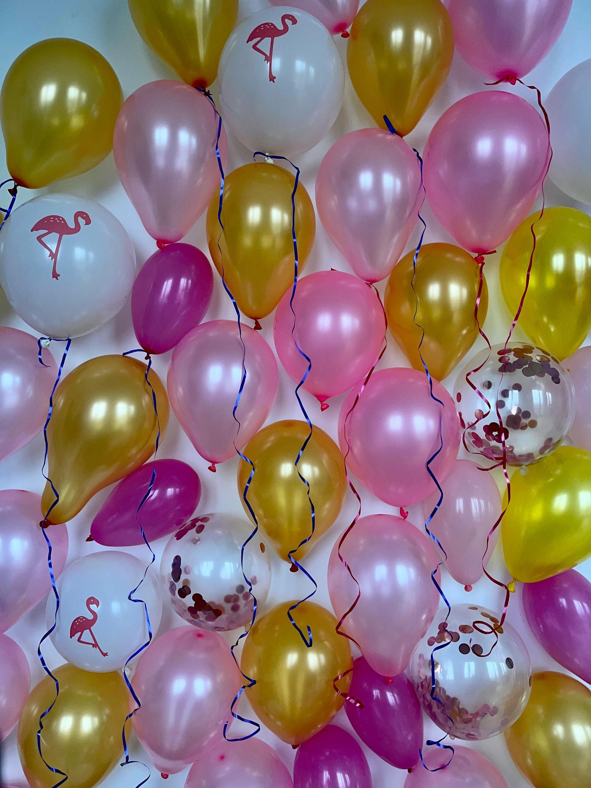 Un cartel con globos y flores está colocado encima de un caballete blanco.